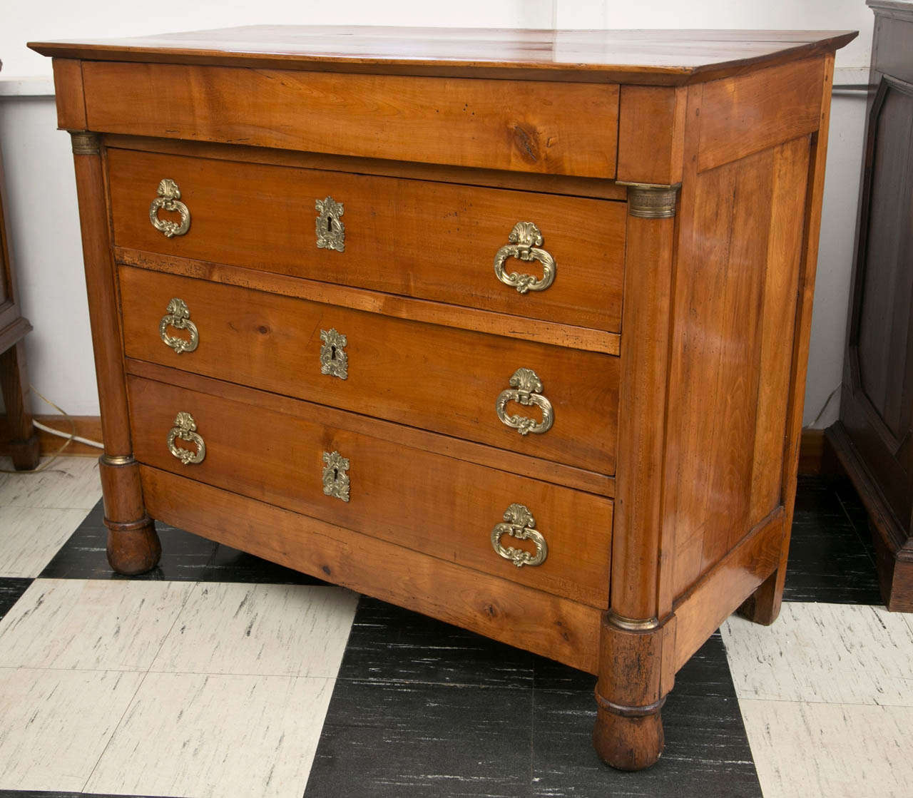 This cherrywood commode has something unusual besides its wood, it has its original bronze hardware. In classic Empire form with brass-mounted columnar sides and a “hidden” top drawer, this chest exhibits an extraordinary patina to go with its overt