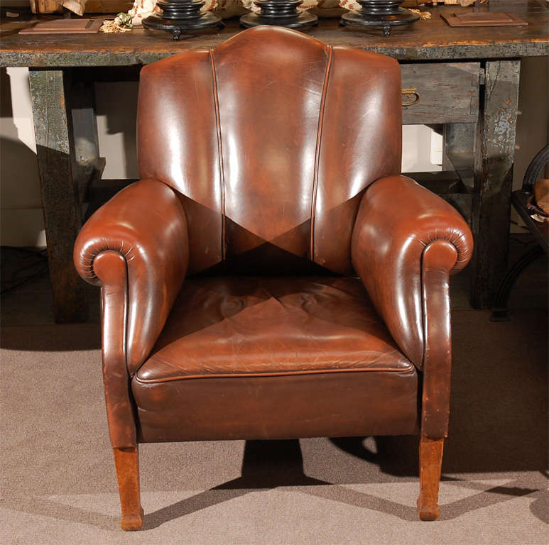 A modern arm chair with a shaped back and padded scroll arms raised on straight legs