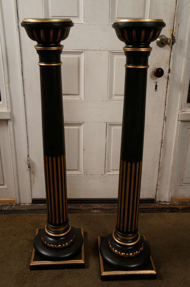 Made in the very late 19th or early 20th century, this pair of carved of pine pedestals are tall and thin and painted a deep rich Verde antique bronze color. The gilding is done in the old world Italian manner of red boule and then gilding over