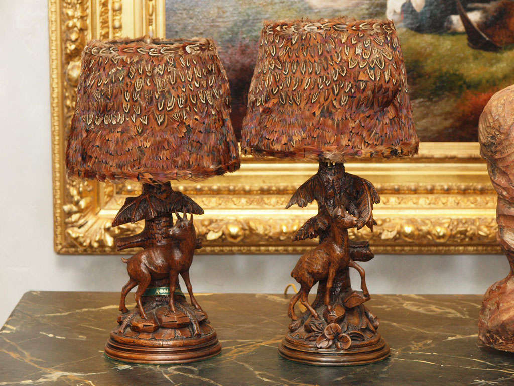 Pair of late 19th century Black Forest carvings, mounted as lamps with feather shades. Carvings depict mountain goats on a rocky base.