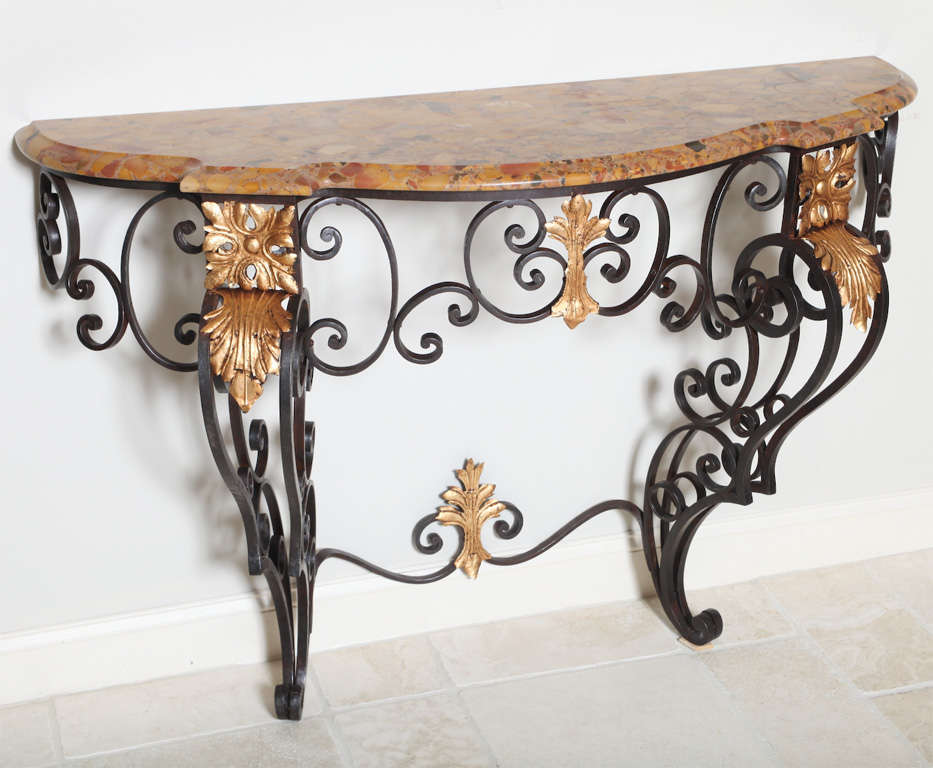 Wall mounted Louis XV style console, in the manner of Gilbert Poillerat, of wrought iron, having a shaped Brèche d'Alep marble top, raised on scrolling black iron base with gilded details.