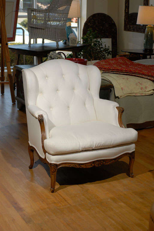 This is a lovely French arm chair.  The arms, legs and apron are beautifully carved.  The chair sits very well.  The button back is surround by wings.  The chair is covered in muslin.  It is ready to be recovered.<br />
<br />
Please visit our