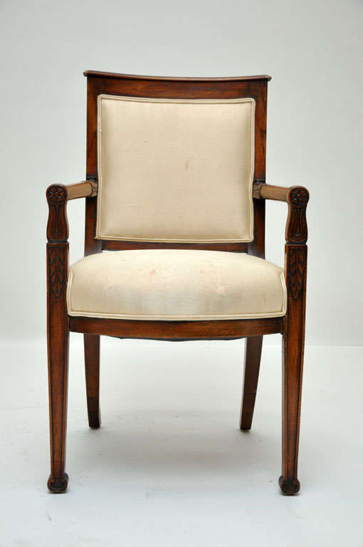 Pair of French mahogany fauteuils or armchairs from the consulate period. Mahogany frame with circular arm rests connecting trapeze shaped back, supported on front square tapered legs and saber back legs are out swept in the shape of a Calvary