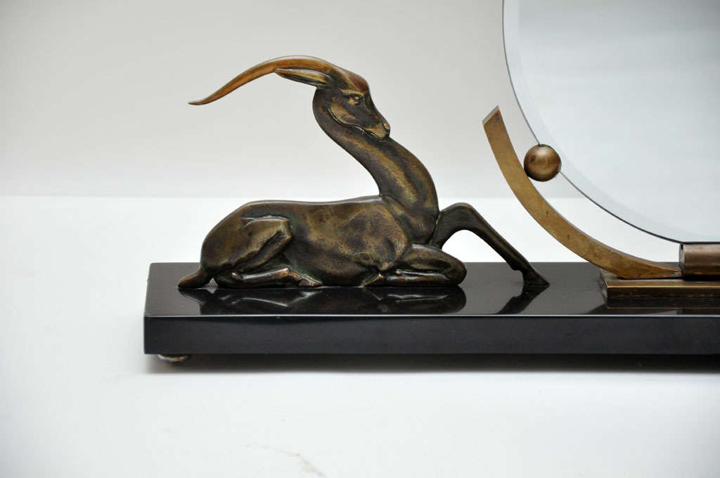 Unique and rare French Art Deco bronze gazelle freestanding mirror with frameless circular mirror accented with pearl-shaped mounts connecting rounded arc bronze support flanked on either side with cast bronze symmetrical elegant stylized resting