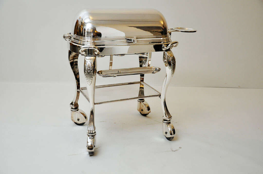 French silver plated meat trolley, revolving dome cover reveals a serving space that includes cutting board and au jus compartments which conceal three burners, to the right of the serving surface is a plate stand, a tray for cutlery is beneath the
