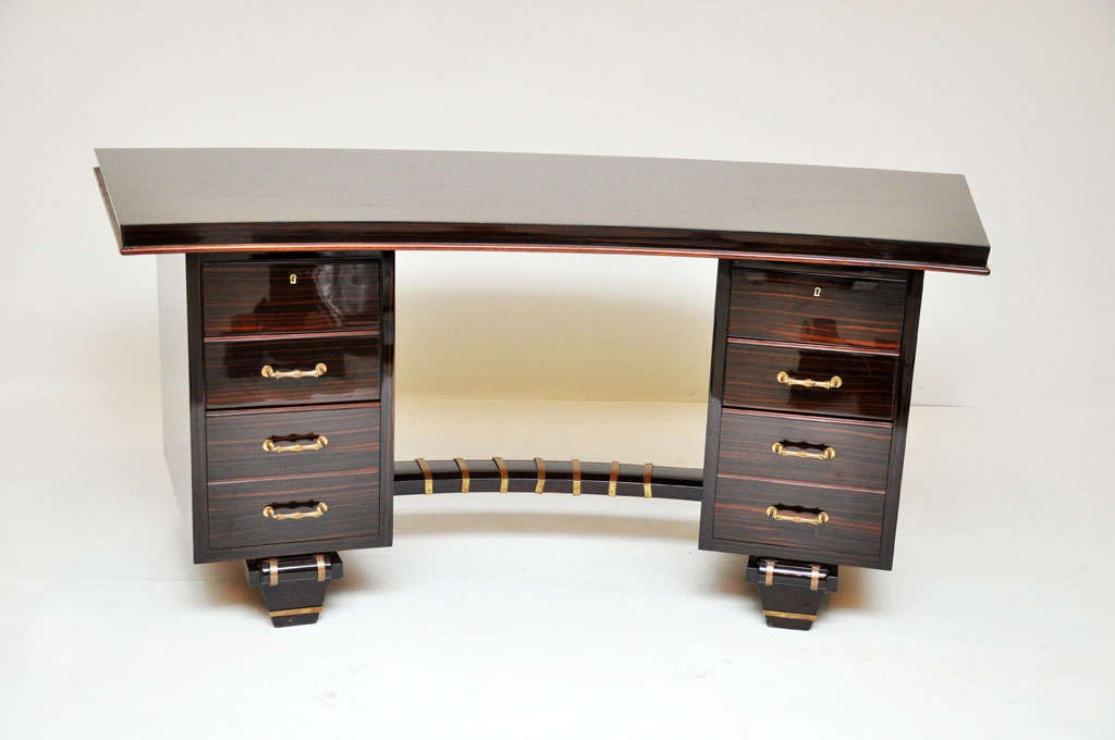 Rare French Art Deco macassar ebony double pedestal desk in the manner of Émile-Jacques Ruhlmann.  Each pedestal containing four drawers with bronze key hole and handles, slightly curved geometric form flat top writing surface bringing the piece