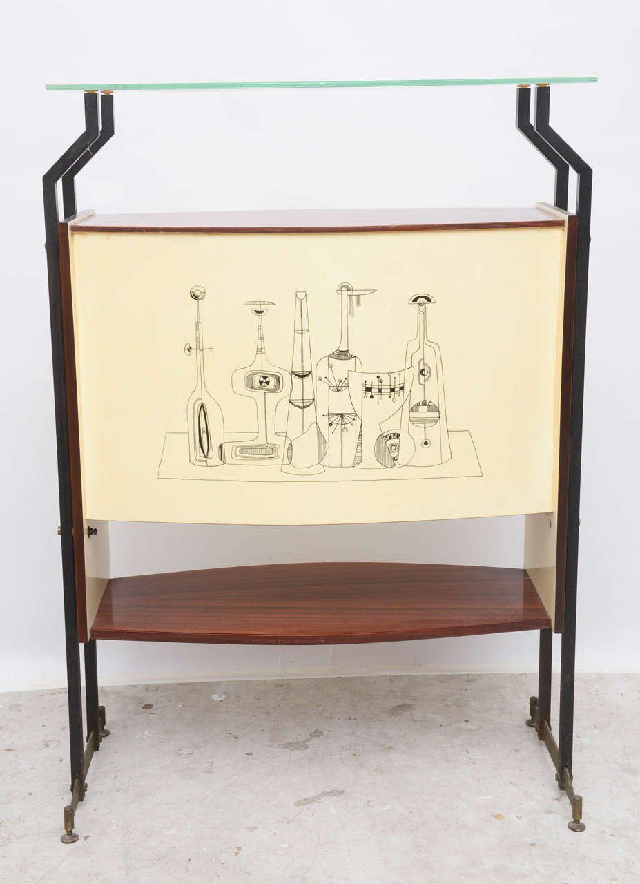 Standing Bar Cabinet attributed to Gio Ponti with 2-door fronts, interior shelf storage space for holding liquor, bar essentials and glasses with front embellished, hand-painted design motif with figural characters.  Wrought iron and brass footed