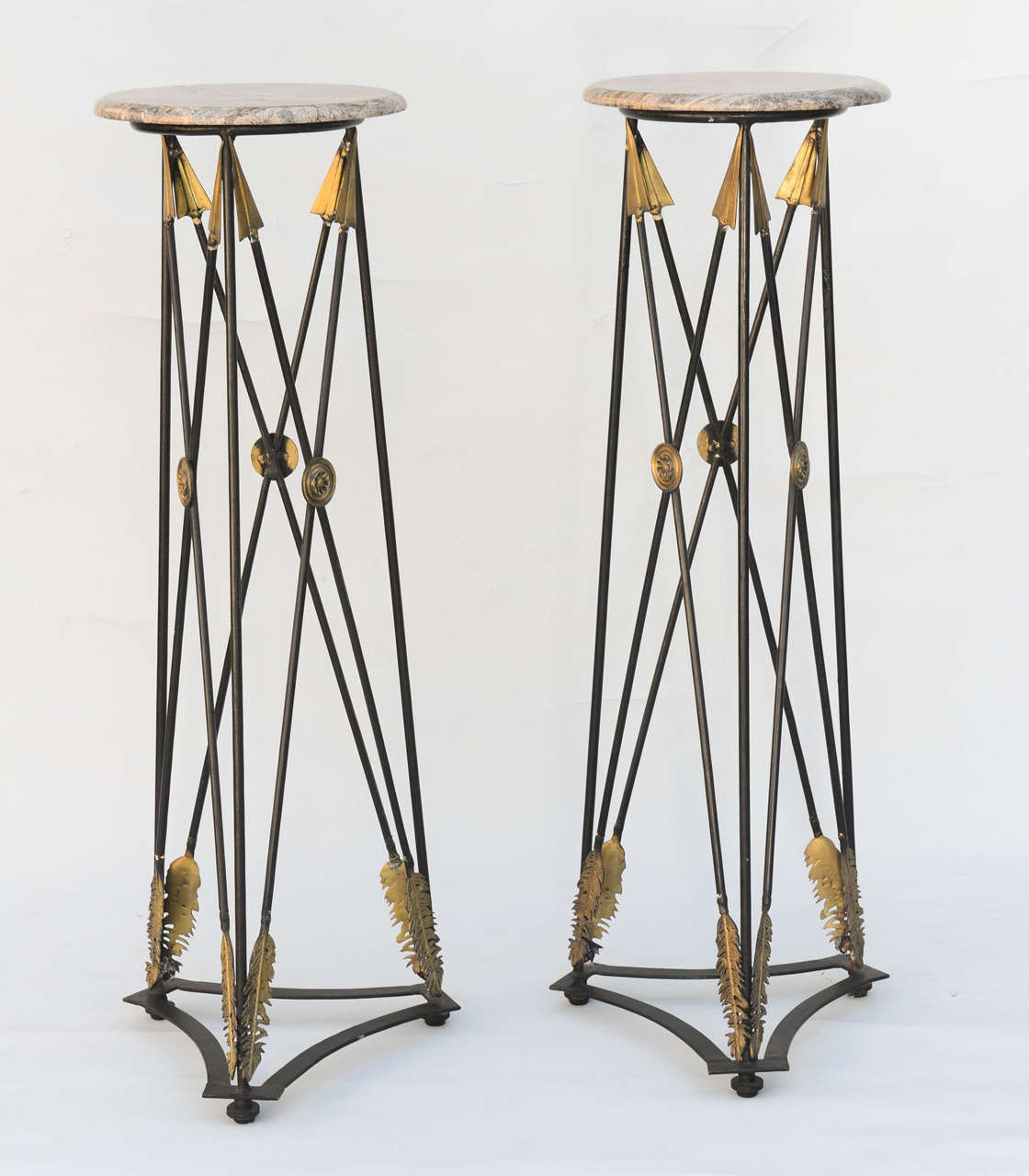 Pair of Directoire-style fern stands, of iron, each having round stone top, raised on iron base of arrows, with gilt accents. Diameter of marble top is 13.25