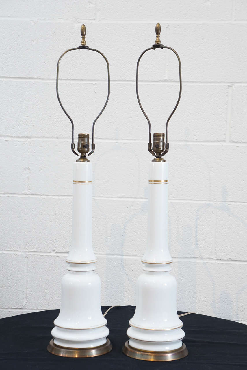 Here is a beautiful pair of white opaline glass lamps with gold trim and brass bases. The lamps are in working order with original wiring.