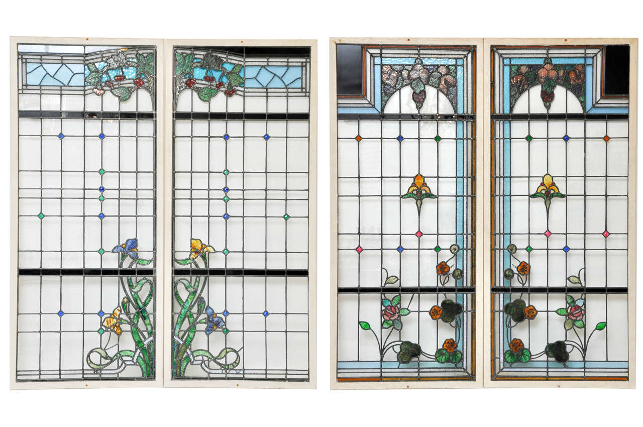 A rare set of four French stained glass windows. Art Nouveau organic design drawing, sky blue trellis with fruit, berries and vines. A clear paned background with flowing stylized violet and mustard yellow lilies with undulating long organic green