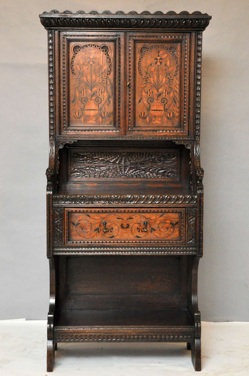 Unique hand-carved cabinet from the Aesthetic Movement in England, to be used as a petite buffet or bar. Top portion of cabinet with beautifully marquetry inlaid panels on each door depicting a vase with flowing stylized flowers, the midsection of