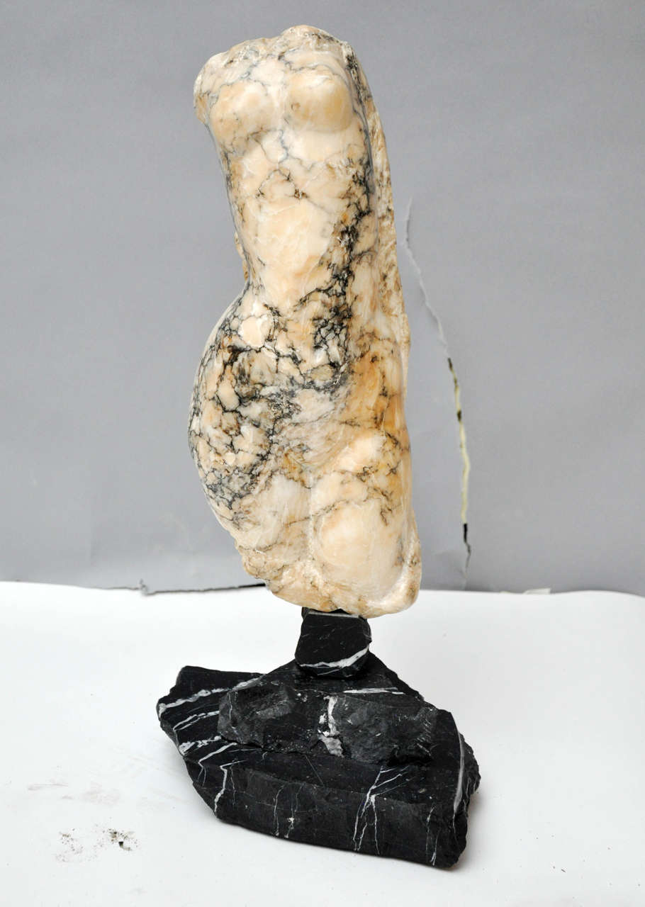 A graceful abstract headless, armless female torso Italian sculpture, hand-carved from an extraordinary cream marble with heavy gray veining, sculpted body seems to be swaying as if dancing, supported on a shapely tiered fragment black marble base