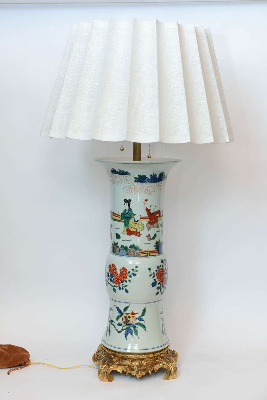 A massive pair of Chinese porcelain gu shaped vase lamps with figurines mounted on a Rococo bronze base, 20th century.