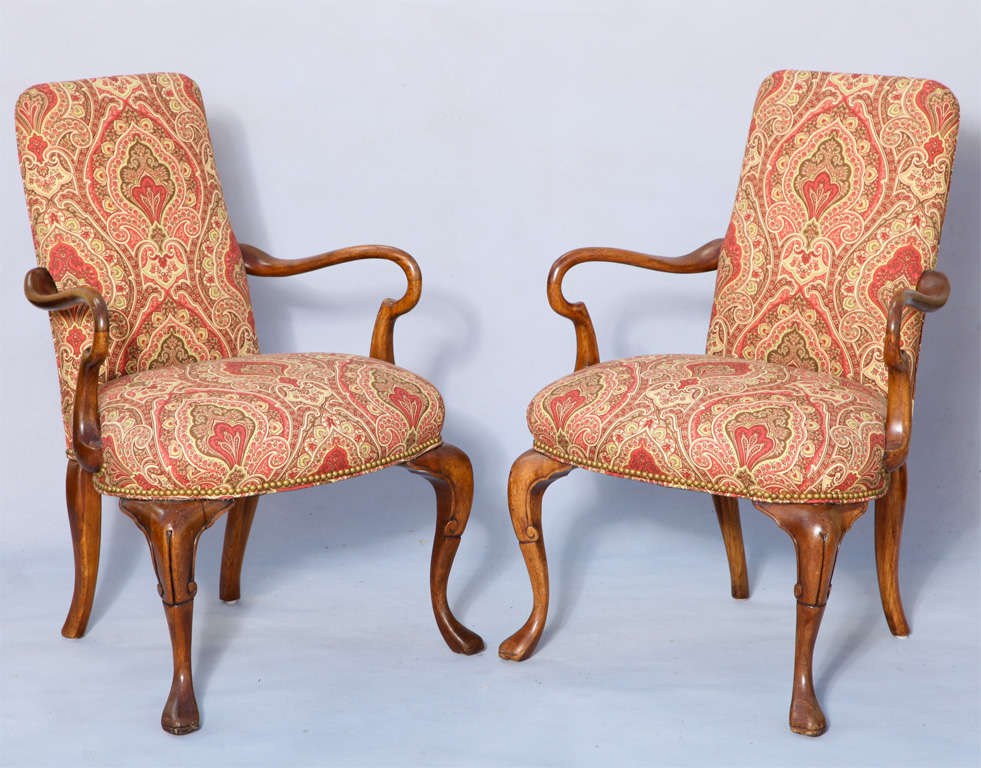 Pair of fanciful open armchairs,of mahogany, each having upholstered back and stuff-over seat, outswept bowed arms, raised on scroll carved cabriole legs. Upholstered in paisley (swatch available)finished with nailheads.