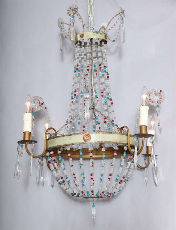 Chandelier in classic European Empire shape with a twist; two painted tole rings with gilt rosettes accent suspended by strings of clear glass beads interjected with turquoise and red, four spiral plumes finished by pendulums, four S-scroll gilded