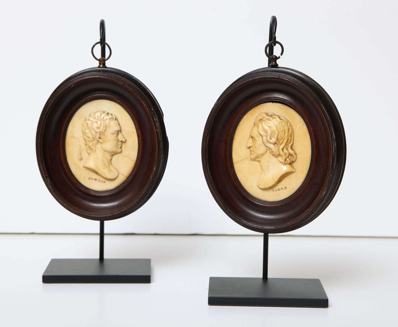 A pair of 19th century English wax oval portrait medallions of John Locke and Sir Isaac Newton set within mahogany frames circa 1820, mounted on contemporary stands