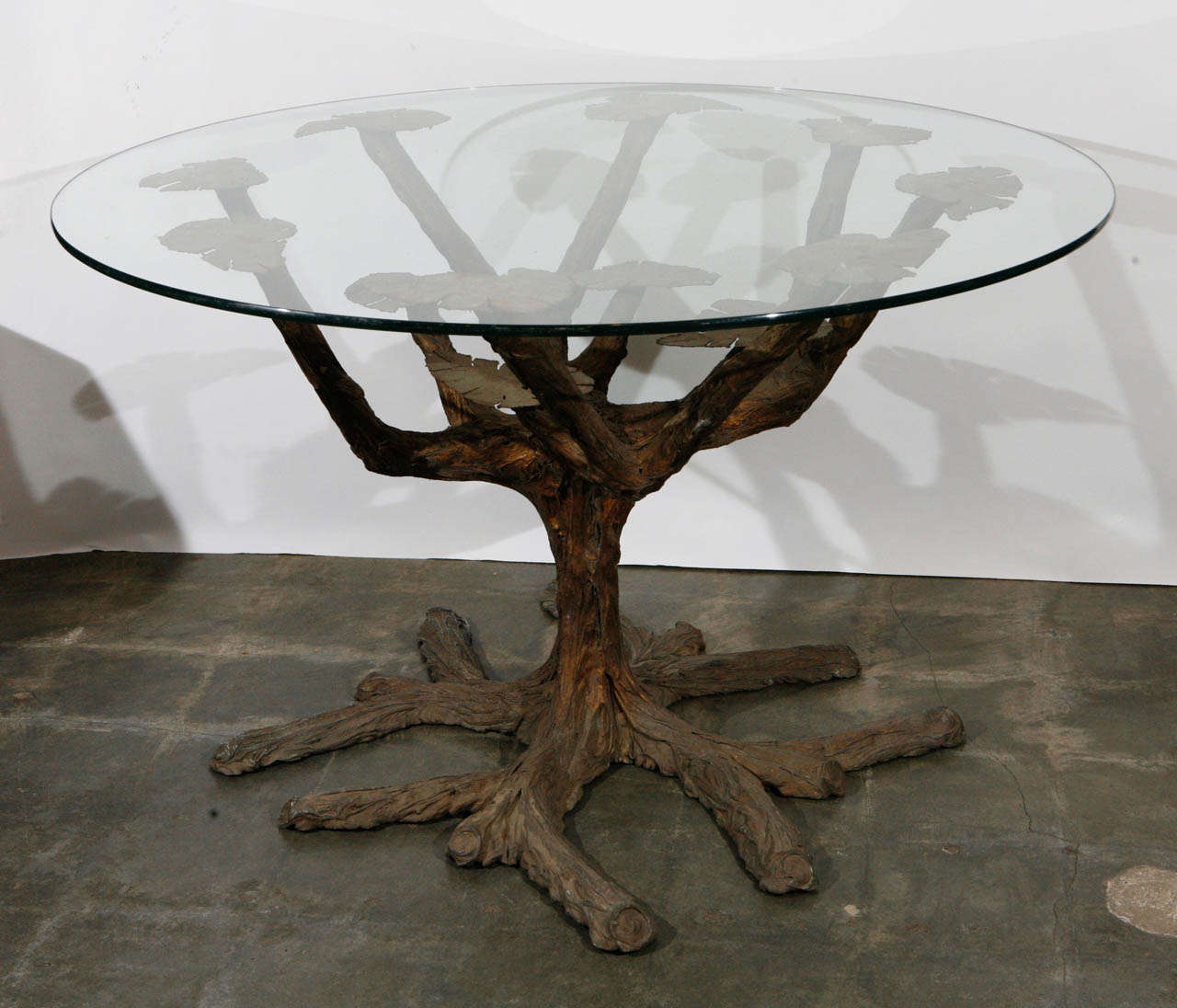 This table base has a very interesting modernist look.   The base is certainly custom made. The basic structure is metal over cement and rebar with a "bark" skin applied by hand. There are surface cracks in the "bark" but are not