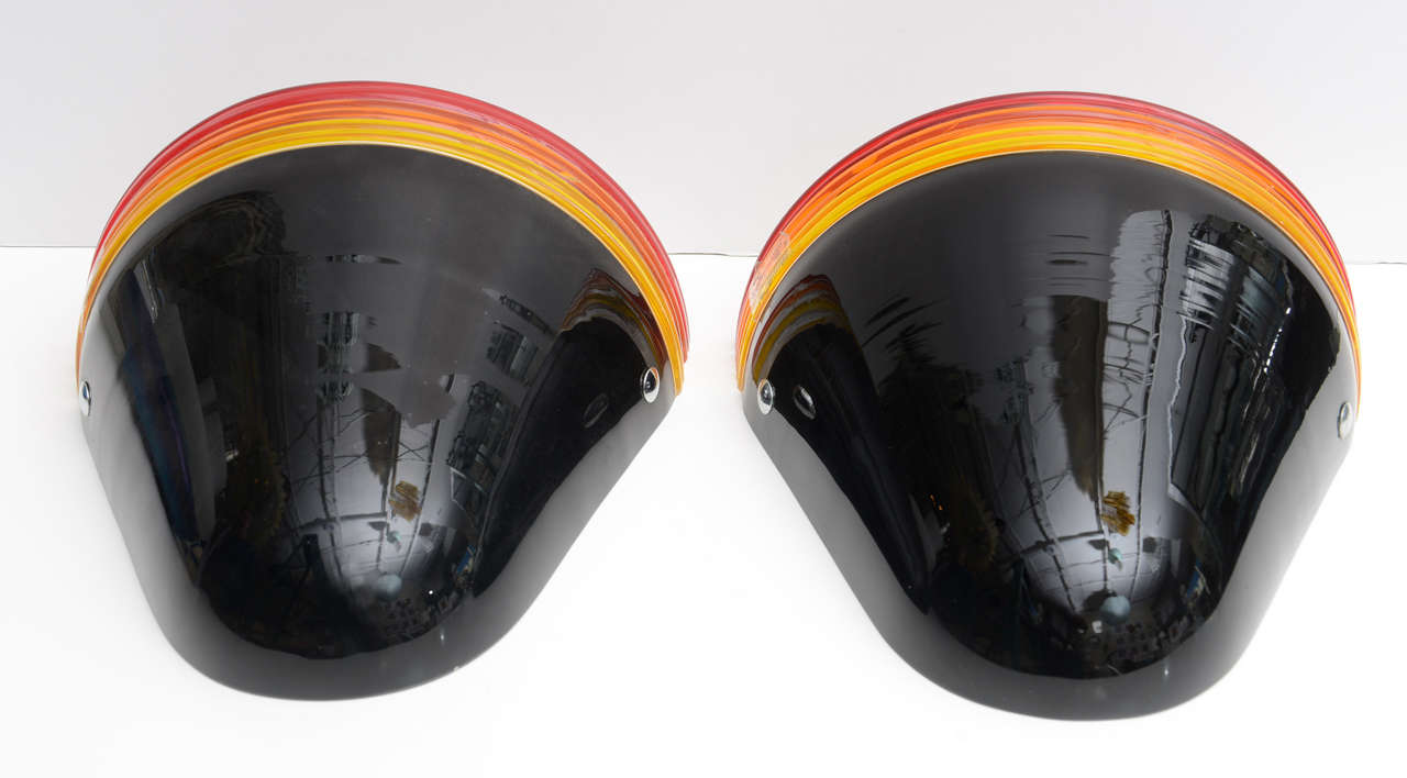Ein Paar Murano-Leuchter aus schwarzem Glas, oben versetzt mit gelben, orangen und roten Glasbändern. Die Wandleuchter sind nicht verkabelt.
Entworfen von Roberto Pamio & Renato Toso für Leucos.