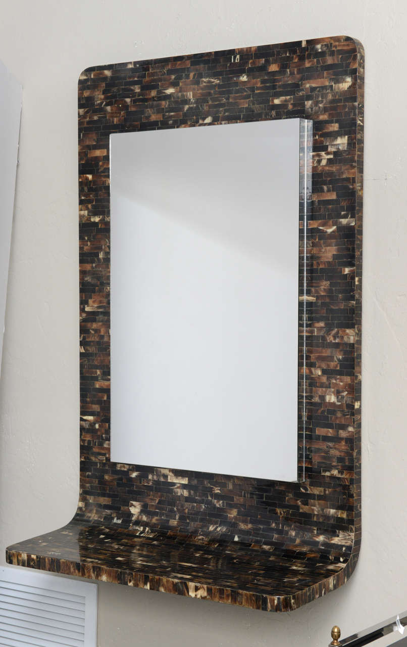 Self framing horn tile mirror gently curves into a shelf at the bottom to create a Minimalist wall-mounted console.