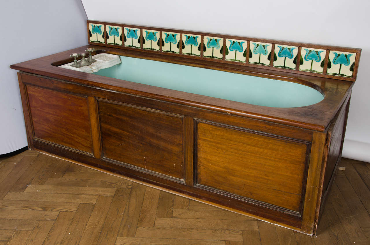 A striking and unique original Edwardian bath with beautiful blue enamel encased in an attractive mahogany unit. The bath has a ceramic shelf with soap holders and original taps at one end. The mahogany unit is in good condition and features a run