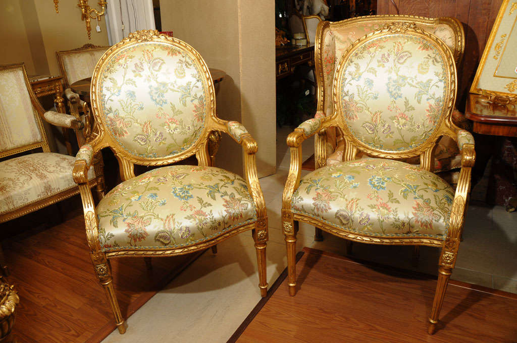 pr of 19thc Louis XVI oal back open arm chairs all hand carved and gilded covered in beautiful silk