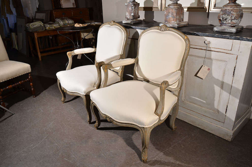 Pair of fauteuils in the style of Louis XV, painted gray-blue long ago, now showing appealing wear. Circa 1850. France. Refurbished, upholstered in simple white cotton.