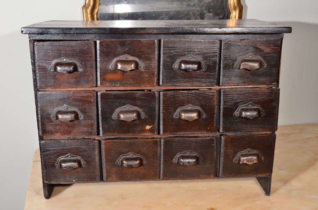 Small, primitive, painted cabinet with 12 drawers, all with bin pulls.