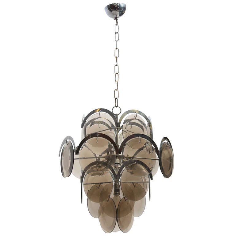 A beautiful four tiers chandelier with mouth-blown and hand-cut-glass discs which gives a beautiful optical effect in the lighting is hung in a crescent-shaped crome frame.
Sockets: 10 x E14 bulbs.