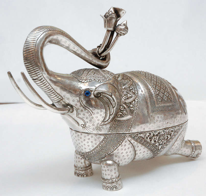 A charming duo of sterling silver elephant boxes, intricately patterned, with their trunks up for good luck. The larger of the two holds flowers in its trunk, which are removable, and is inset with a pair of sapphire colored crystals for its eyes.