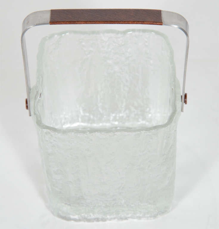 Mid-Century Modern personal ice bucket with textured ice glass design. The ice bucket includes stainless steel tongs and draining tray, and has a stainless steel handle with leatherette trim in brown.