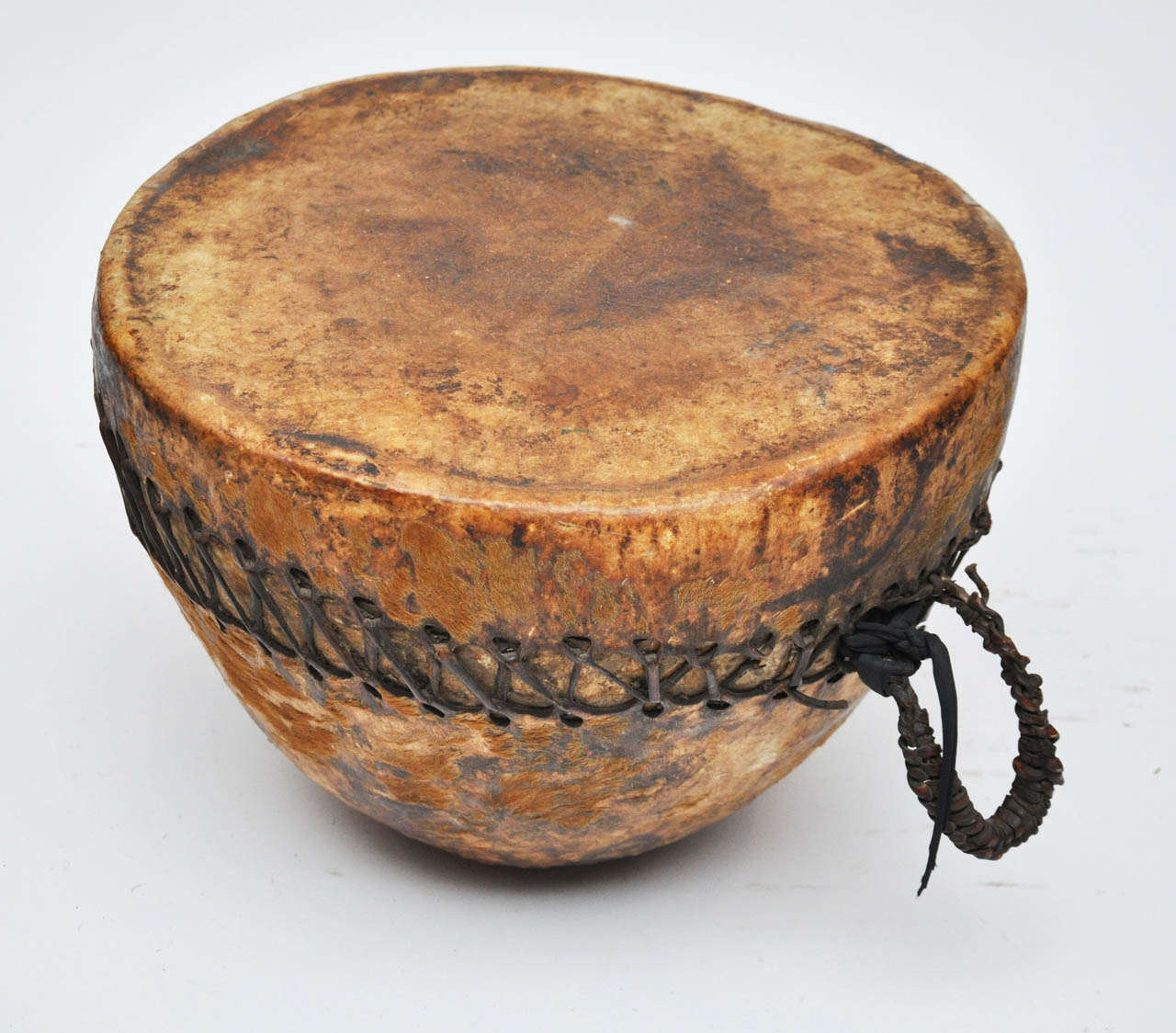 Ethiopian ceremonial hand drum used for religious and secular celebrations. The bottom of the drum is covered in animal skin and the top is stretched with rawhide. Leather binds and secures the two.