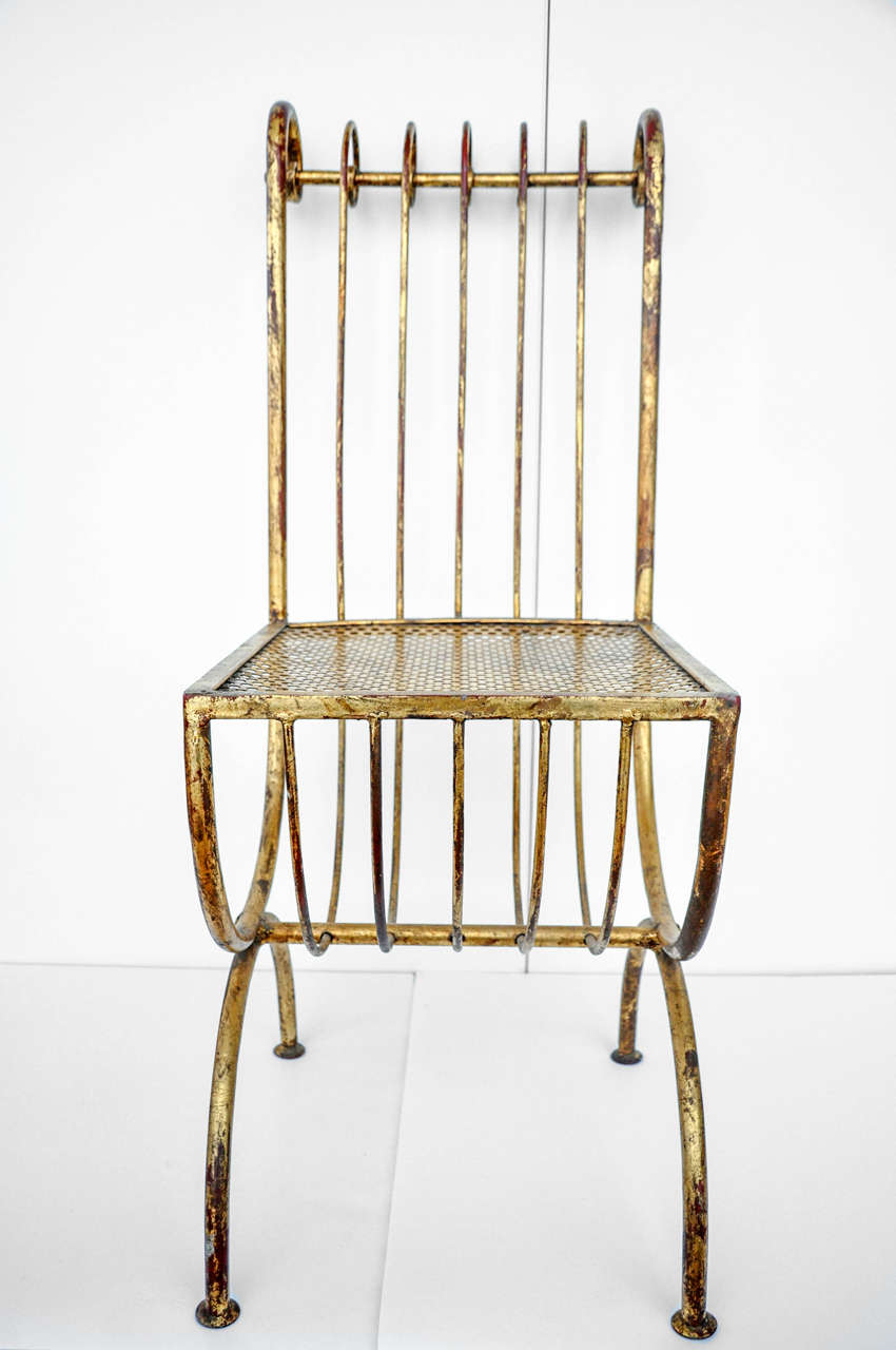 A gilt iron side chair with a sculptural scroll back form, perforated seat and pod feet. This versatile chair is very well-made with a sophisticated design. Though there is some wear to patina, as is typical of these Mid-Century gilt iron pieces,