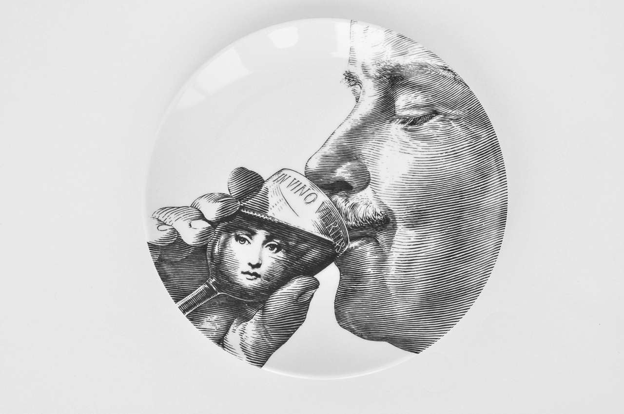 An early production plate by Fornasetti showing the designer drinking wine from a glass that reads 