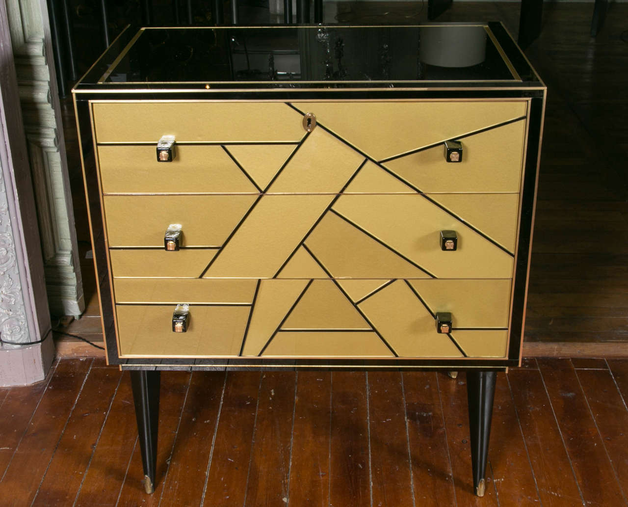 Pair of black and gold mirrored commodes, rare geometrical design on front, opening by three drawers