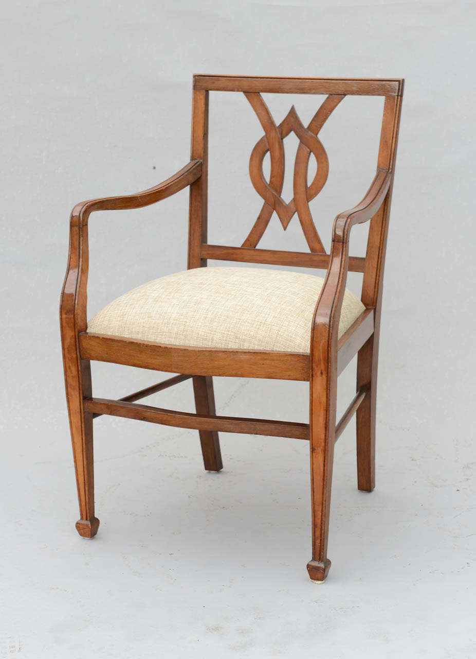 Pair of armchairs, of walnut, each having a square back with intertwined pierced splat, bowed arms continuing to downswept terminals, crown seat on curved rail, raised on square-section tapering legs with squared touipe feet.