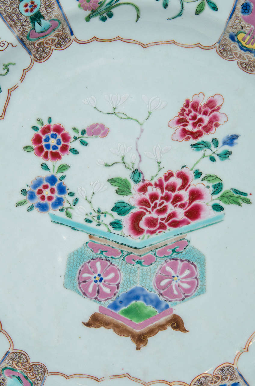 A large Chinese famille rose charger painted in pastel colors of pinks, turquoise, green and blue showing a vase filled with peonies and flowers. In Chinese tradition peonies are known as the king of flowers and symbolize royalty and wealth. The