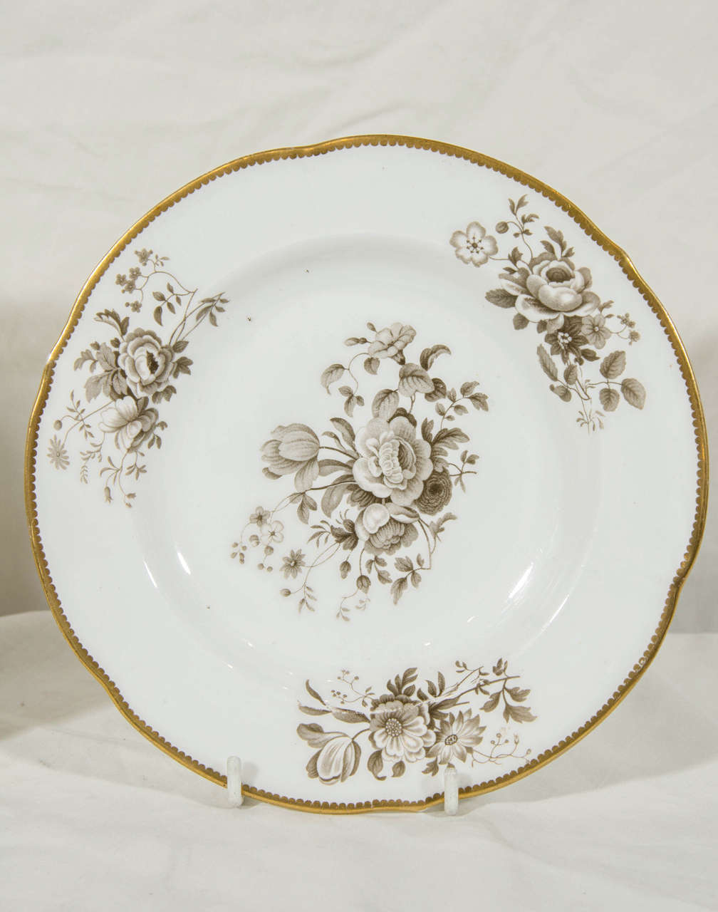 This set of nine Minton dishes are decorated with bouquets of spring flowers painted in grisaille. This design was quite popular in the Early Victorian Period. Each dish has a beautifully gilded, softly lobed border.