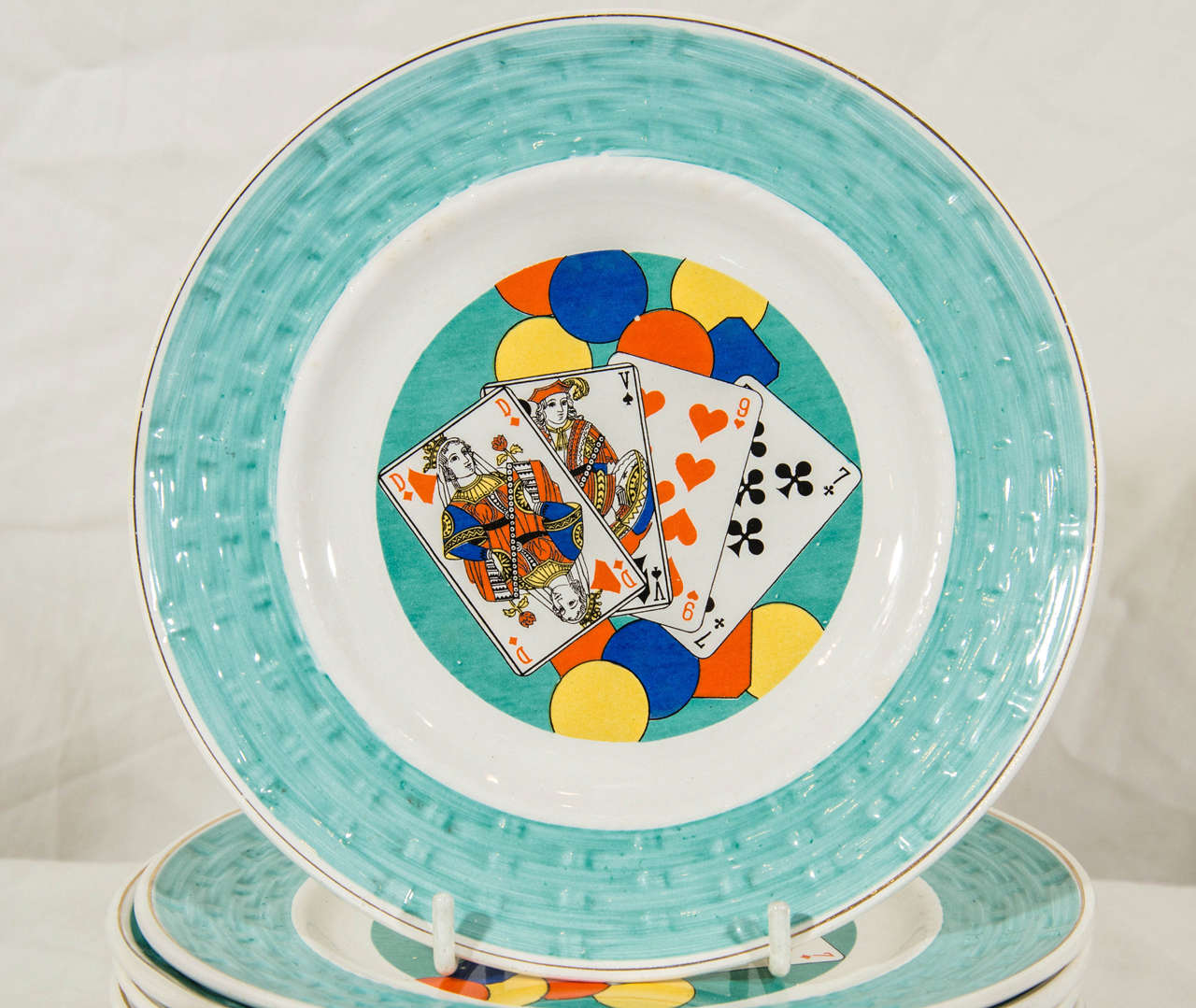 A set of brightly colored French pottery dessert dishes showing playing cards resting on colorful balloons. The borders are impressed with a basket weave design.