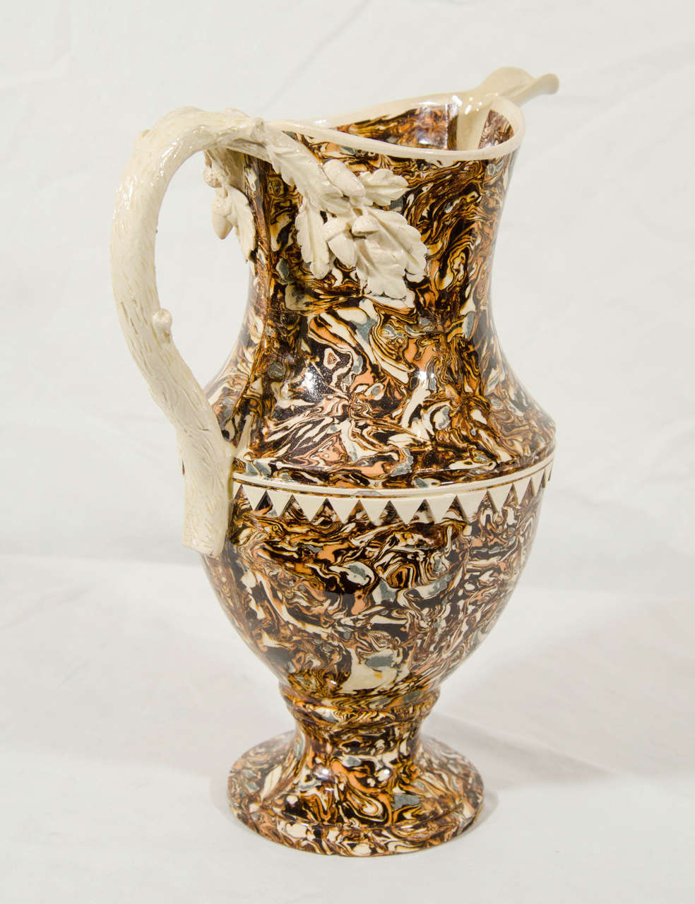 A French, mixed earths, Apt ware pitcher decorated with brown, black and cream colored earthenware (terre mêlée). The tight multicolored patterns were formed by wedging colored clays together, cutting and rolling them like pastry, before molding