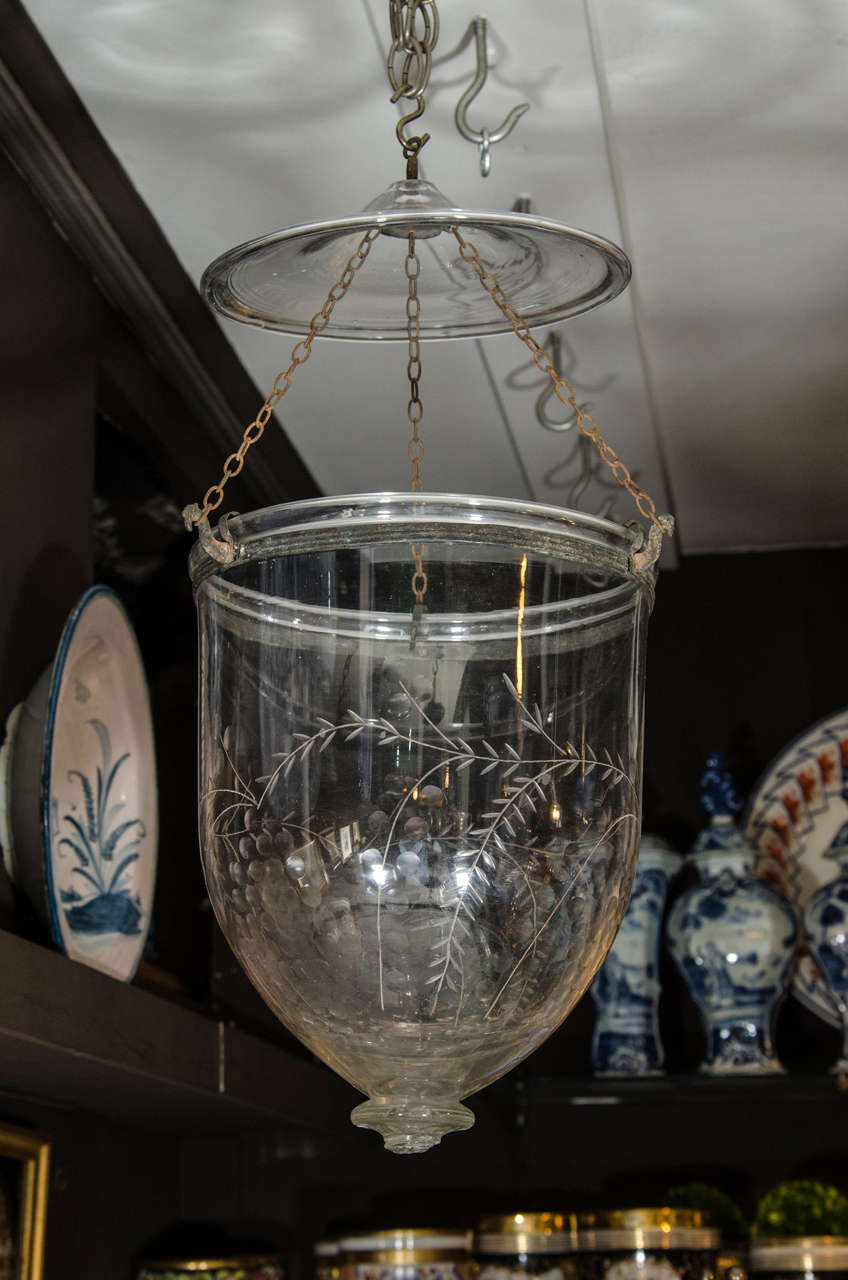 We are pleased to offer this 19th century English bell lantern etched with a lovely floral design of grapes and grape leaves. 
It hangs from its smoke cowl and has a metal collar around the rim.
 In the 19th century this lantern would have held a