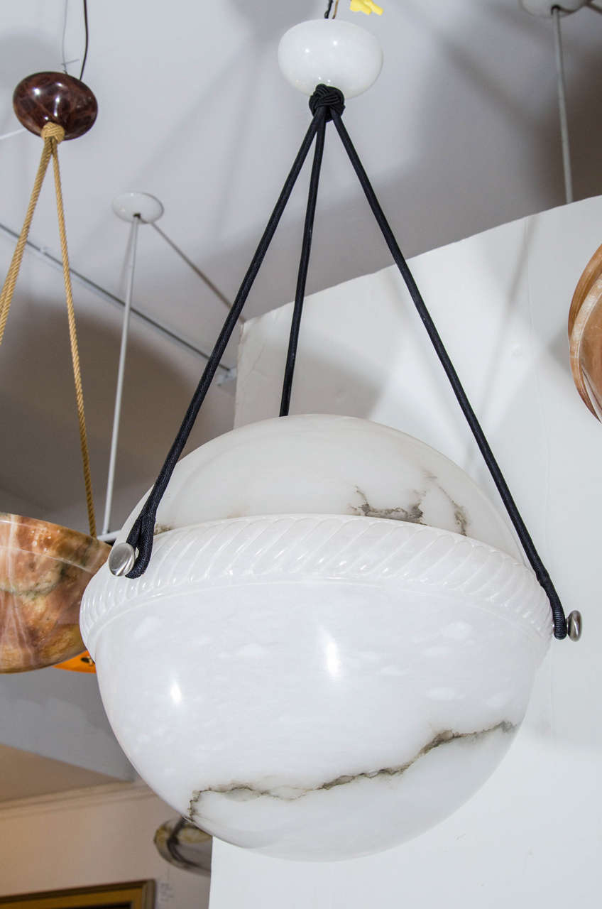 Creamy white alabaster adorned with a meandering ribbon of black mineral veining, the upper half of the fixture rests on a band of twisted alabaster roping. Recently rewired, the fixture holds one 100 watt incandescent bulb or the LED
