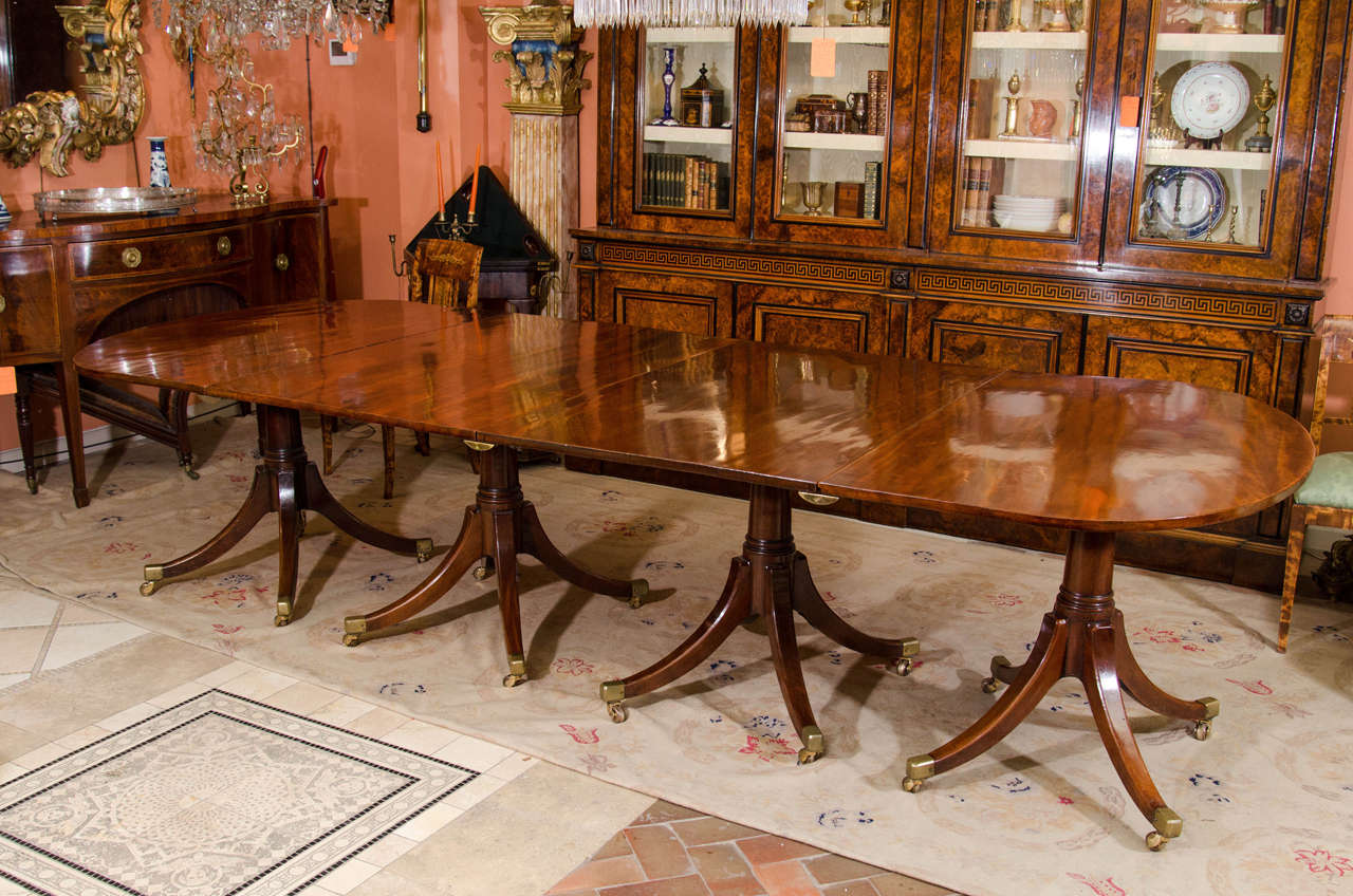 A George III mahogany 4-pedestal dining table with rounded ends and on gunbarrel column quatropod supports ending in brass casters.  With three leaves of later date measuring 20.25