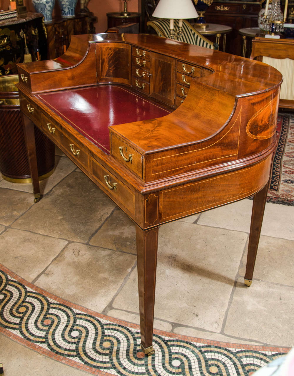 A George III style mahogany crossbanded and line inlaid Carlton House desk with an inset red leather writing surface, on tapering square legs ending in casters.