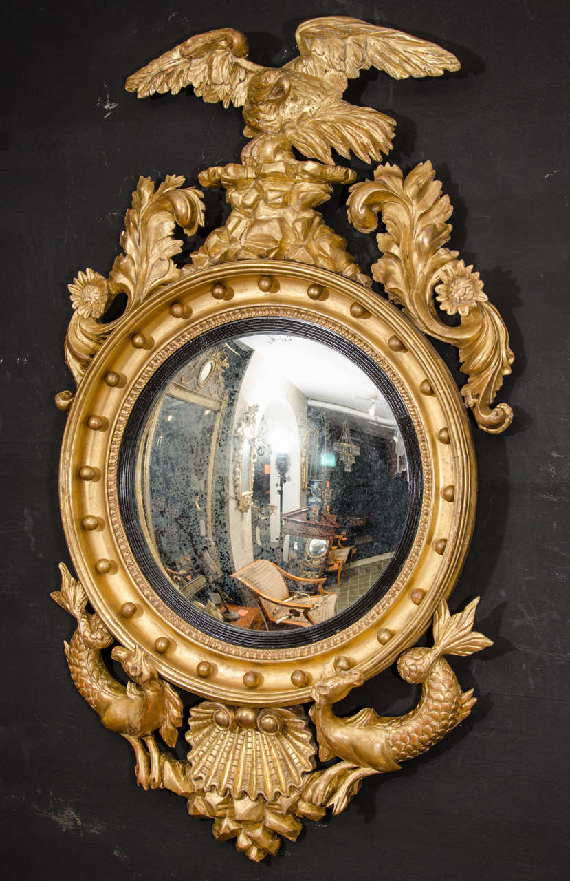 Fine Regency giltwood convex mirror with eagle crest and sunflower and foliate shoulders, a double hippocampus and scallop shell drop. Possibly American.