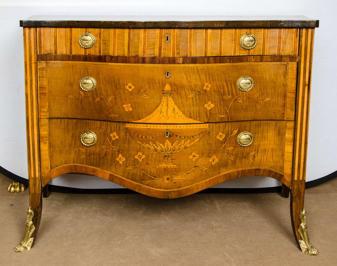 A fine George III marquetry commode, the top is inlaid with a central ribbon-tied spray on rosewood ground and engraved garland flanked by further sprays; all surrounded by stringing and cross banding, a frieze drawer above with two long drawers