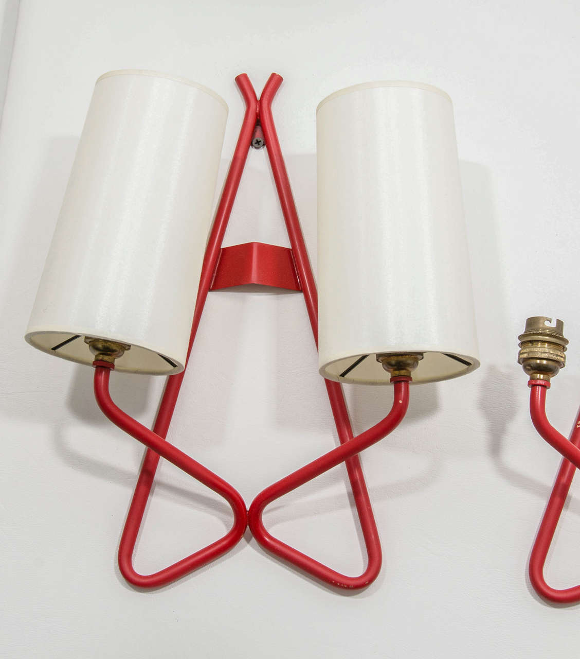 Pair of vermilion iron sconces in the manner of Jean Royere,. Bayonet sockets with silk shades