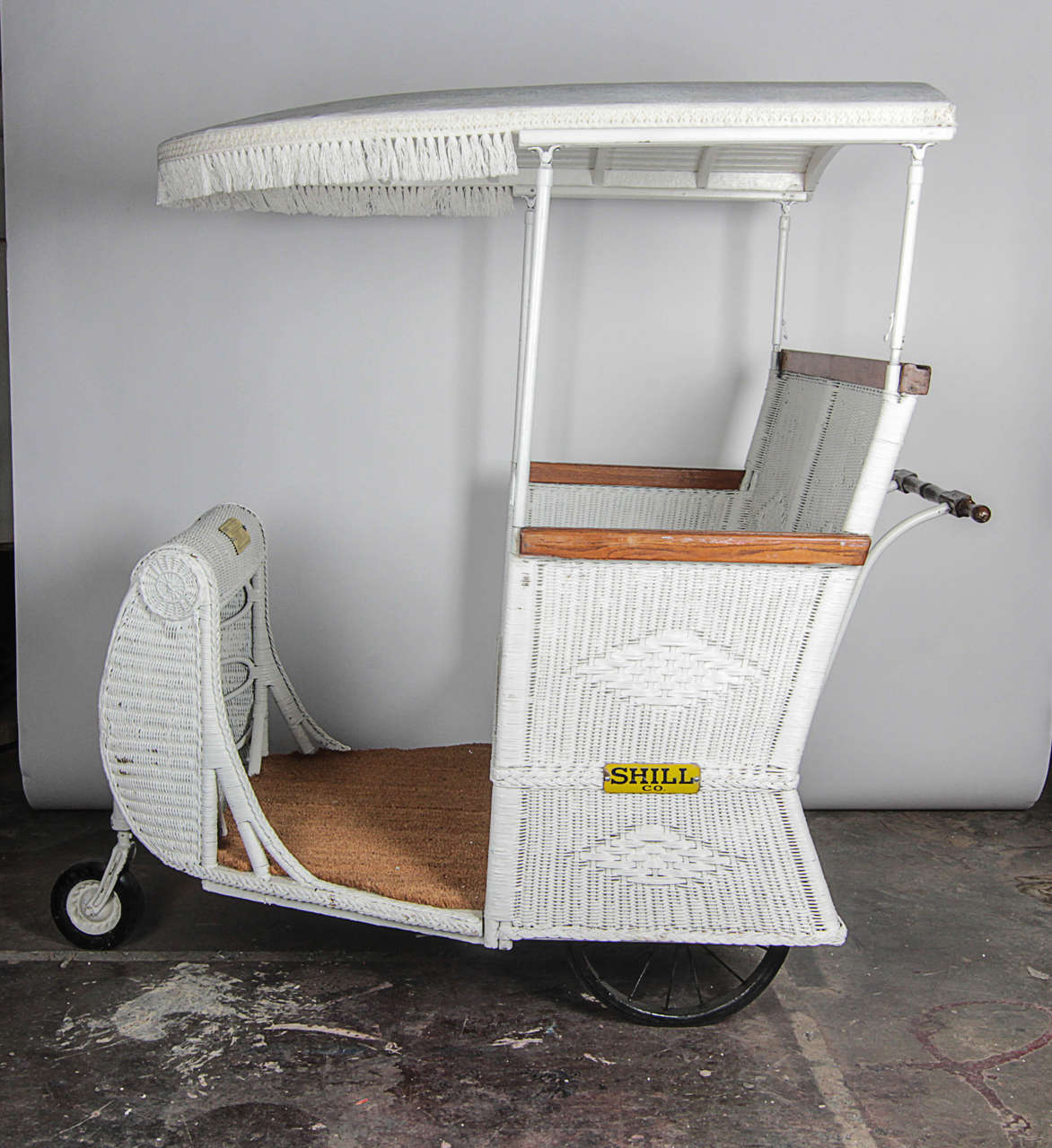 From the era of Boardwalk Empire, this piece of actual history is hard to find. Produced by the Shill Rolling Chair Co., this Mid-Century wicker cart has a license which expired July 1, 1963 (pictured).The original seat has been removed. Carpet