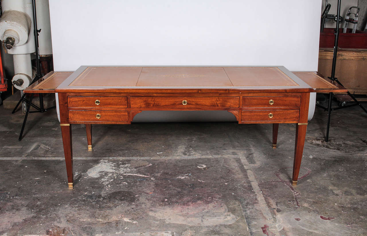 Antique desk made of beautiful mahogany wood. The surface has a leather inset with gilt embossed frieze. Matching sleeves slide from both ends of the desk for additional surface space. Five lockable dovetailed drawers with brass hardware and keys