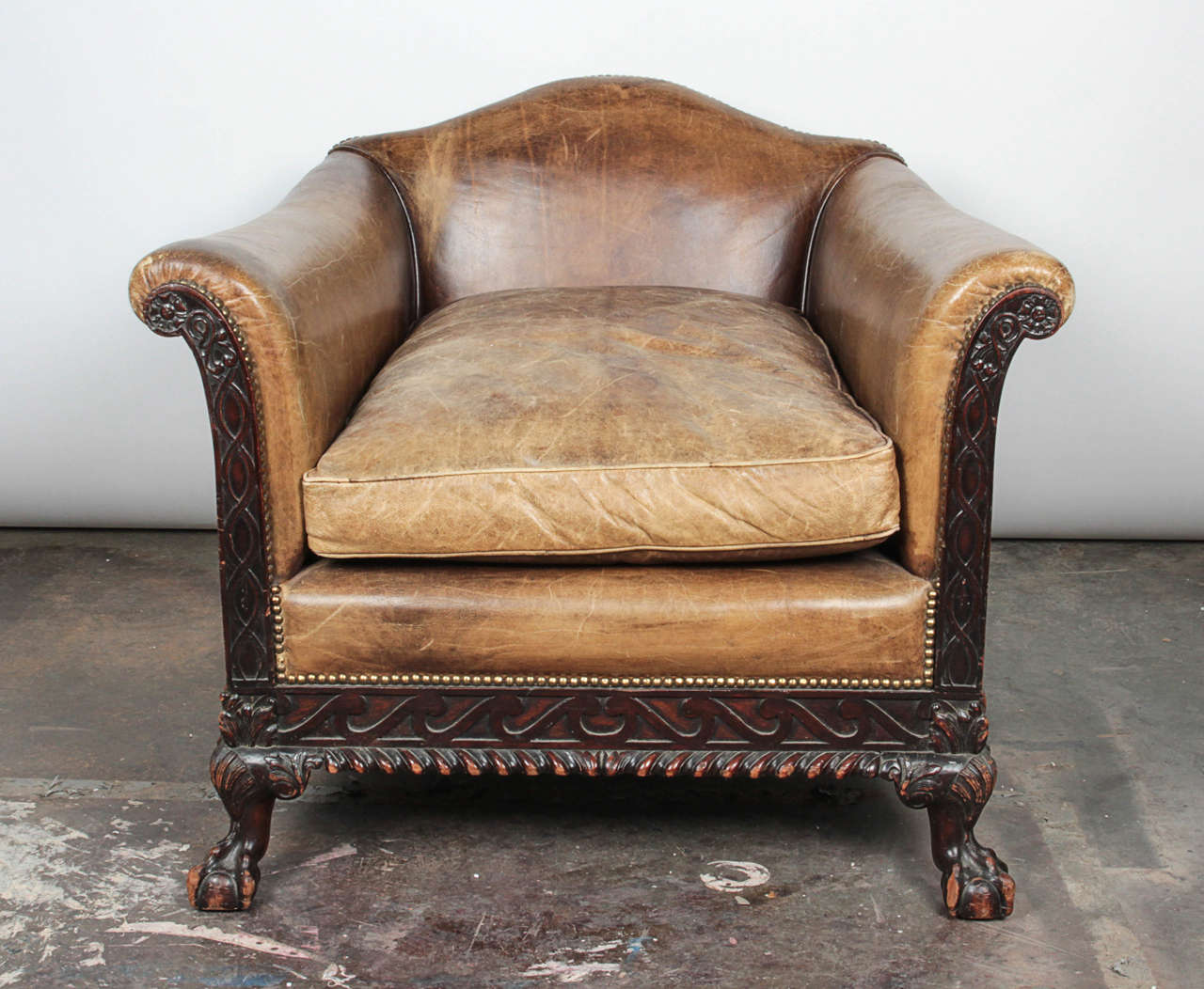 Aged leather and finely carved wooden details add significant character to this intriguing antique. Brass nailhead trim accentuates the curves of the arms and sides of the chair. 

Not available for sale or to ship in the state of California.