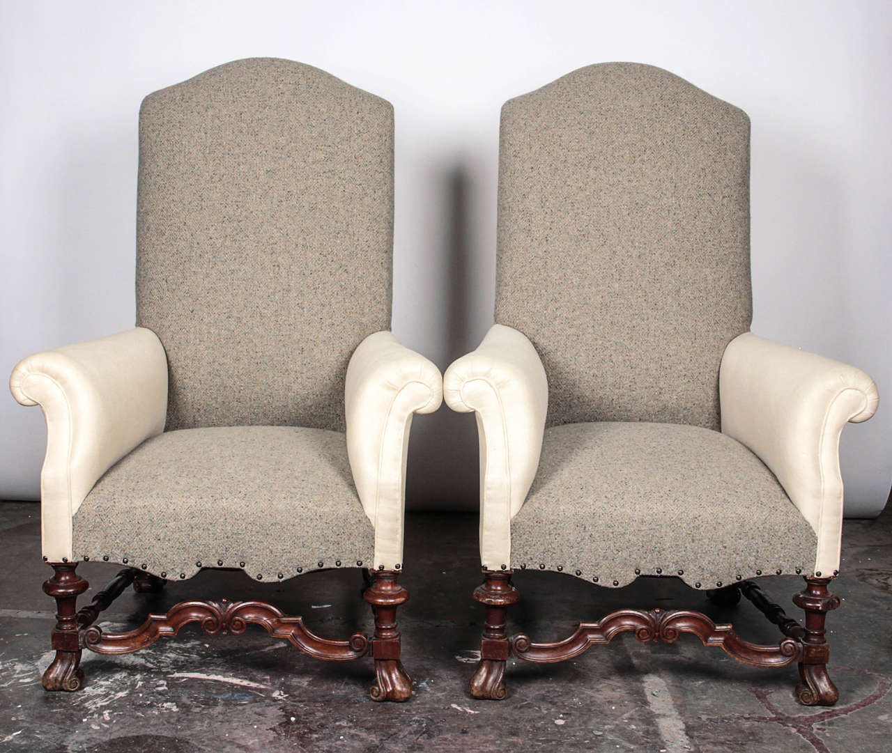 Pair of Queen Anne style armchairs with arched backrest, flared scroll arms, over carved blocked and turned legs joined by a molded arched stretcher. Covered in a combination of linen and wool fabrics with brass tack trim.

Not available for sale
